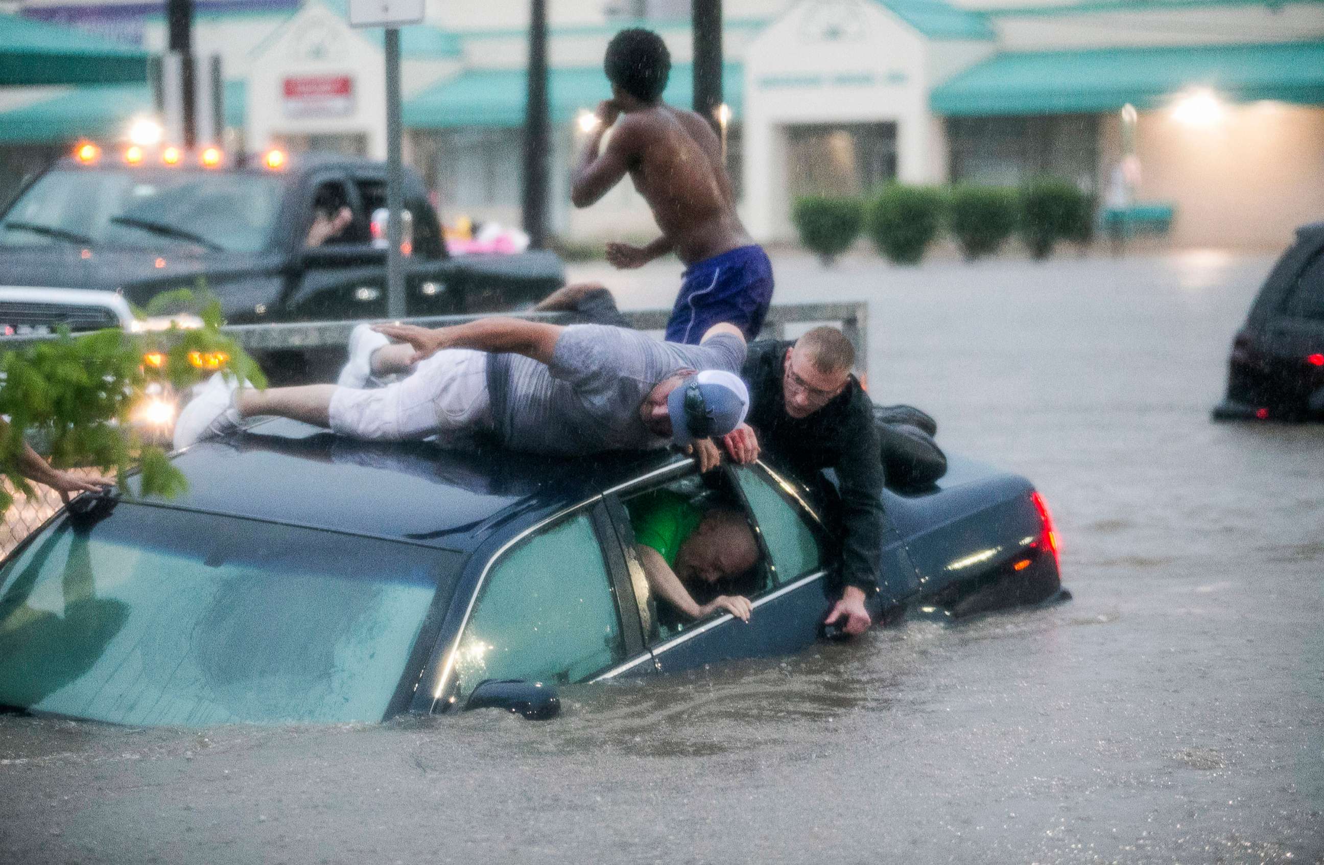 PHOTO: Mark Pickett, left, and Ryan Craig, right, work to rescue Bruce Salley, who was trapped in his car by flood waters in a supermarket parking in Rockford, Ill., June 18, 2018.