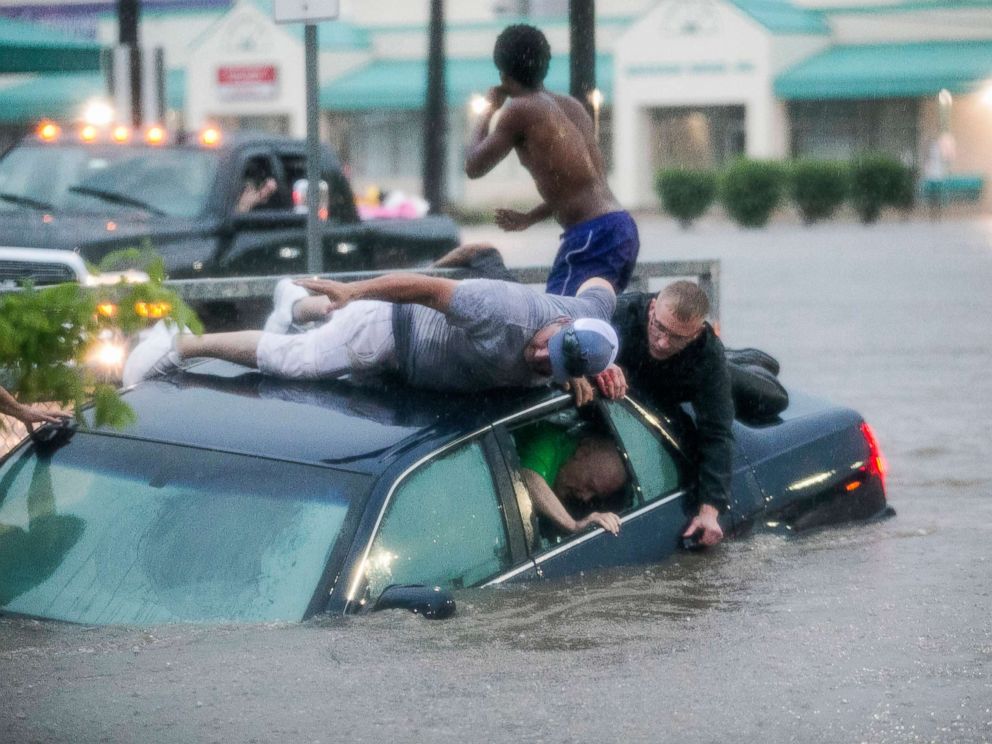 PHOTO: Mark Pickett, left, and Ryan Craig, right, work to rescue Bruce Salley, who was trapped in his car by flood waters in a supermarket parking in Rockford, Ill., June 18, 2018.