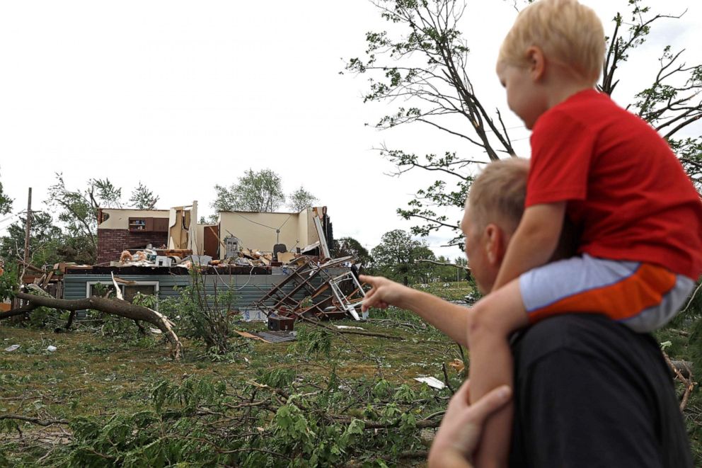 PHOTO: Woodridge, Ill., resident Jesse Wallace points out one of the severely damaged homes to his three-year-old son Chris Wallace, after a tornado passed through the area, June 21, 2021.