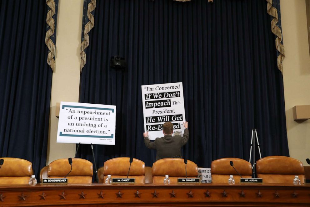 PHOTO: A congressional staffer puts up signs prior to testimony by constitutional scholars before the House Judiciary Committee in the Longworth House Office Building on Capitol Hill, Dec. 4, 2019, in Washington.