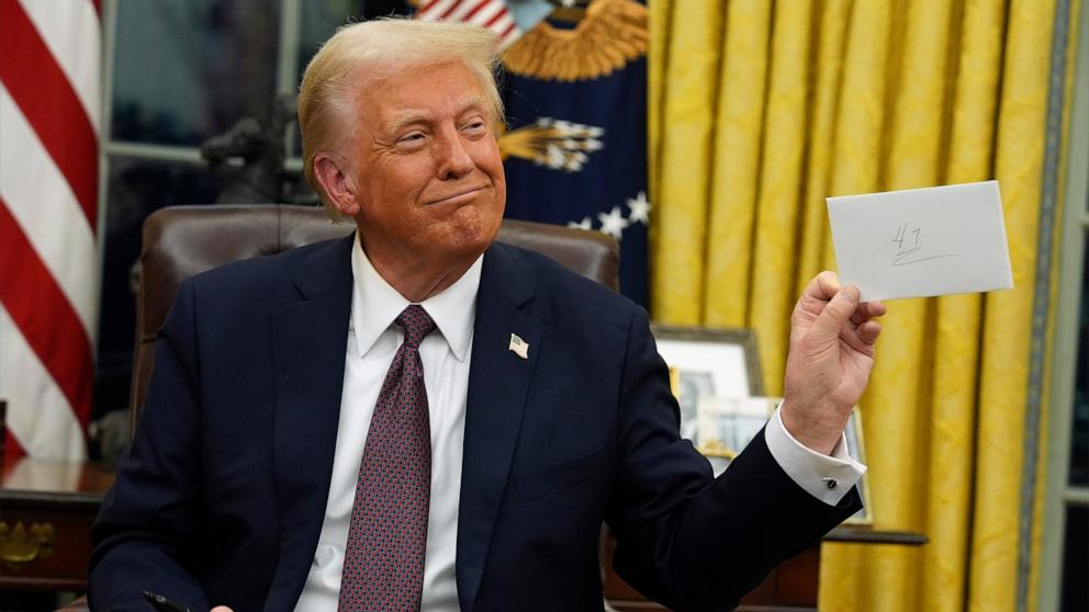 PHOTO: President Donald Trump holds up outgoing President Joe Biden's letter as he signs executive orders in the Oval Office of the WHite House in Washington, Jan. 20, 2025.