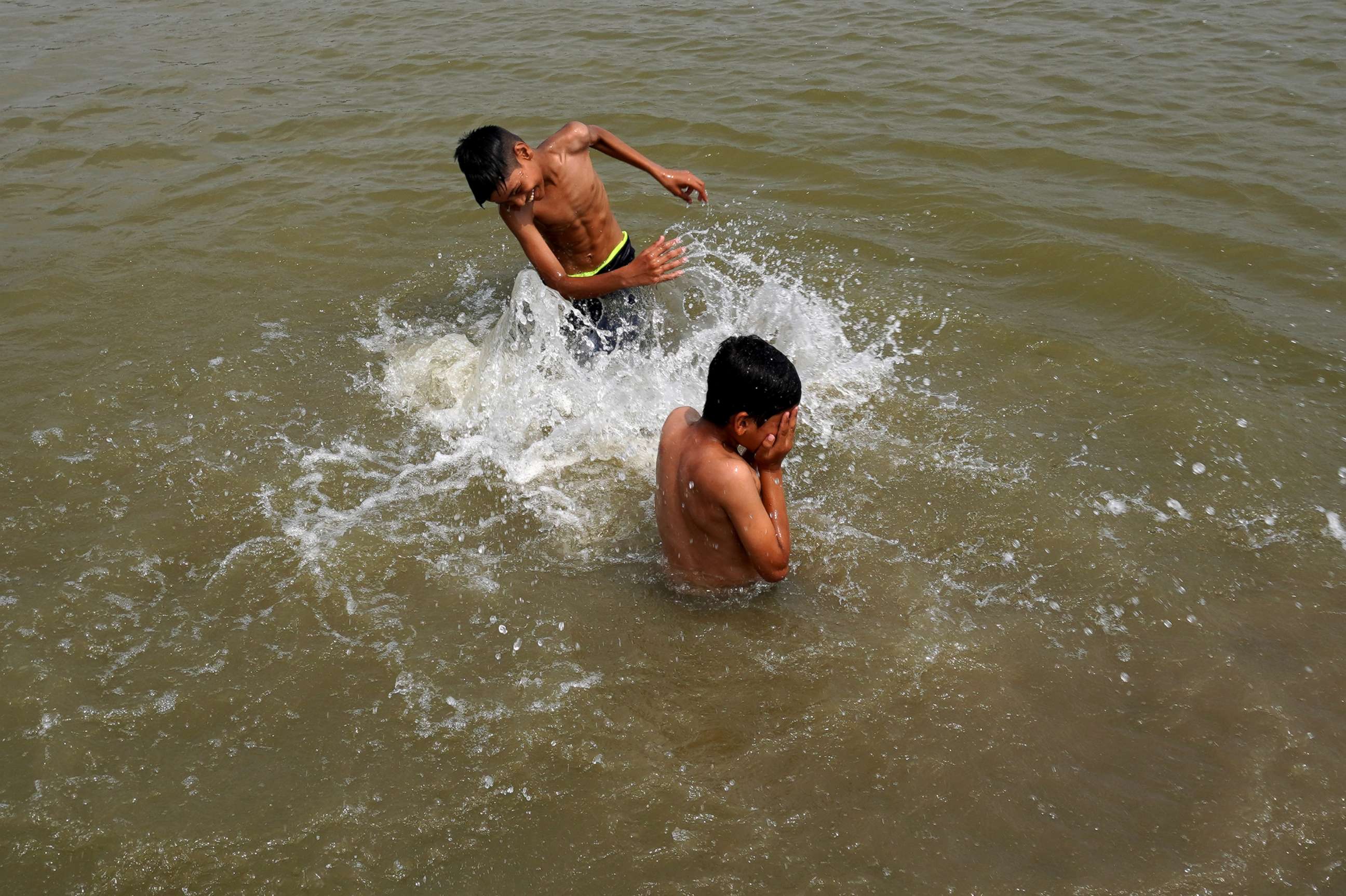 PHOTO: Boys splash water on each other as they swim in a pond on a hot summer day, amid the ongoing heatwave in New Delhi, India, June 27, 2022. 