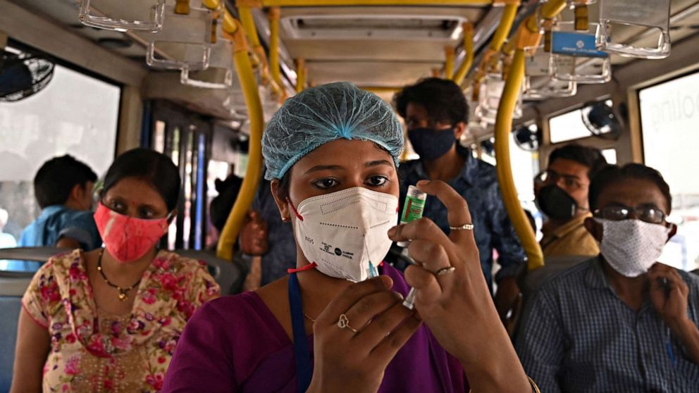 PHOTO: A health worker prepares to inoculate a laborer with the first dose of Covishield vaccine against the COVID-19 in a passenger bus converted into a mobile vaccination center at a market in Kolkata, India on June 3, 2021.