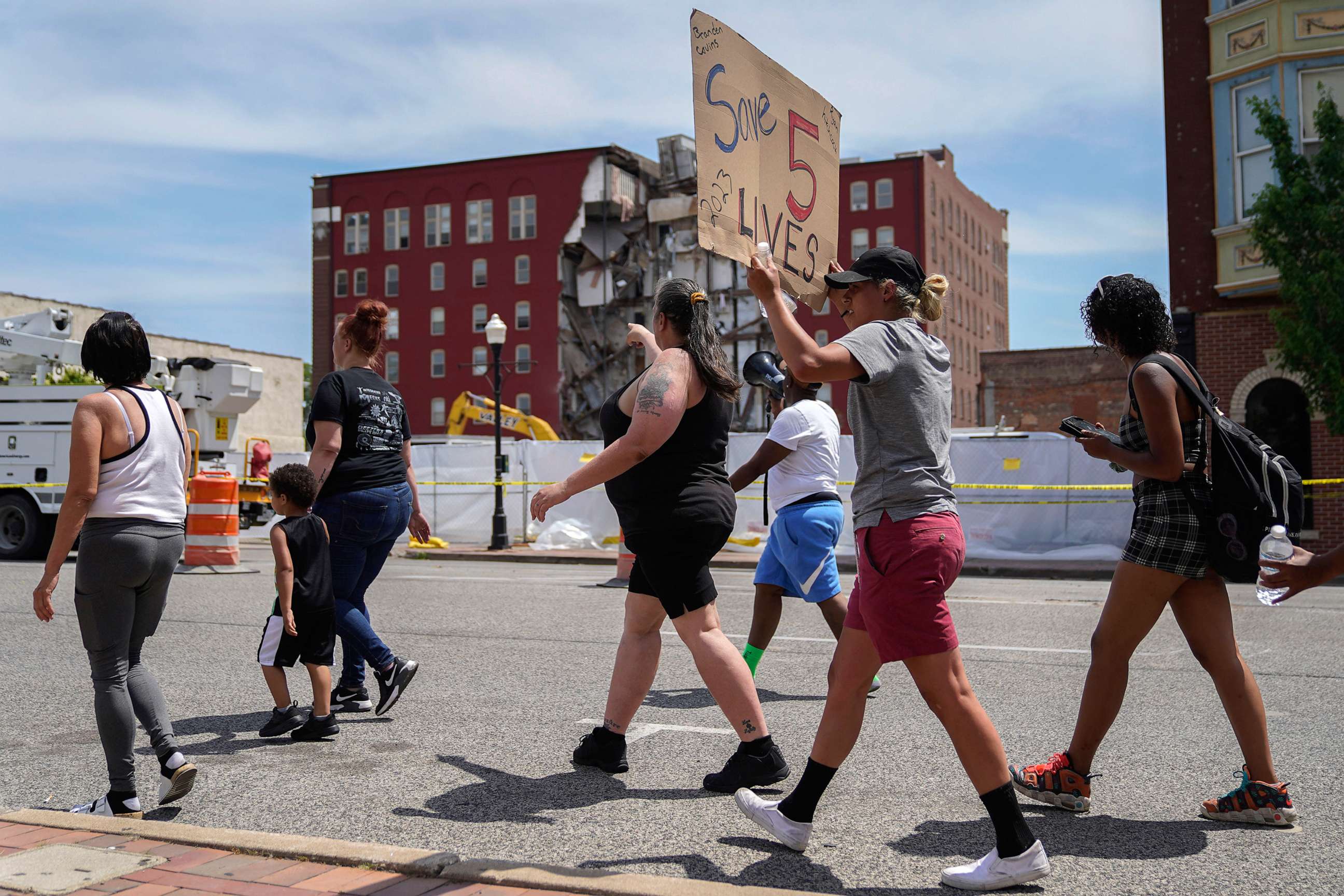 PHOTO: Protesters march in the street near the apartment building that partially collapsed in Davenport, Iowa, May 31, 2023.