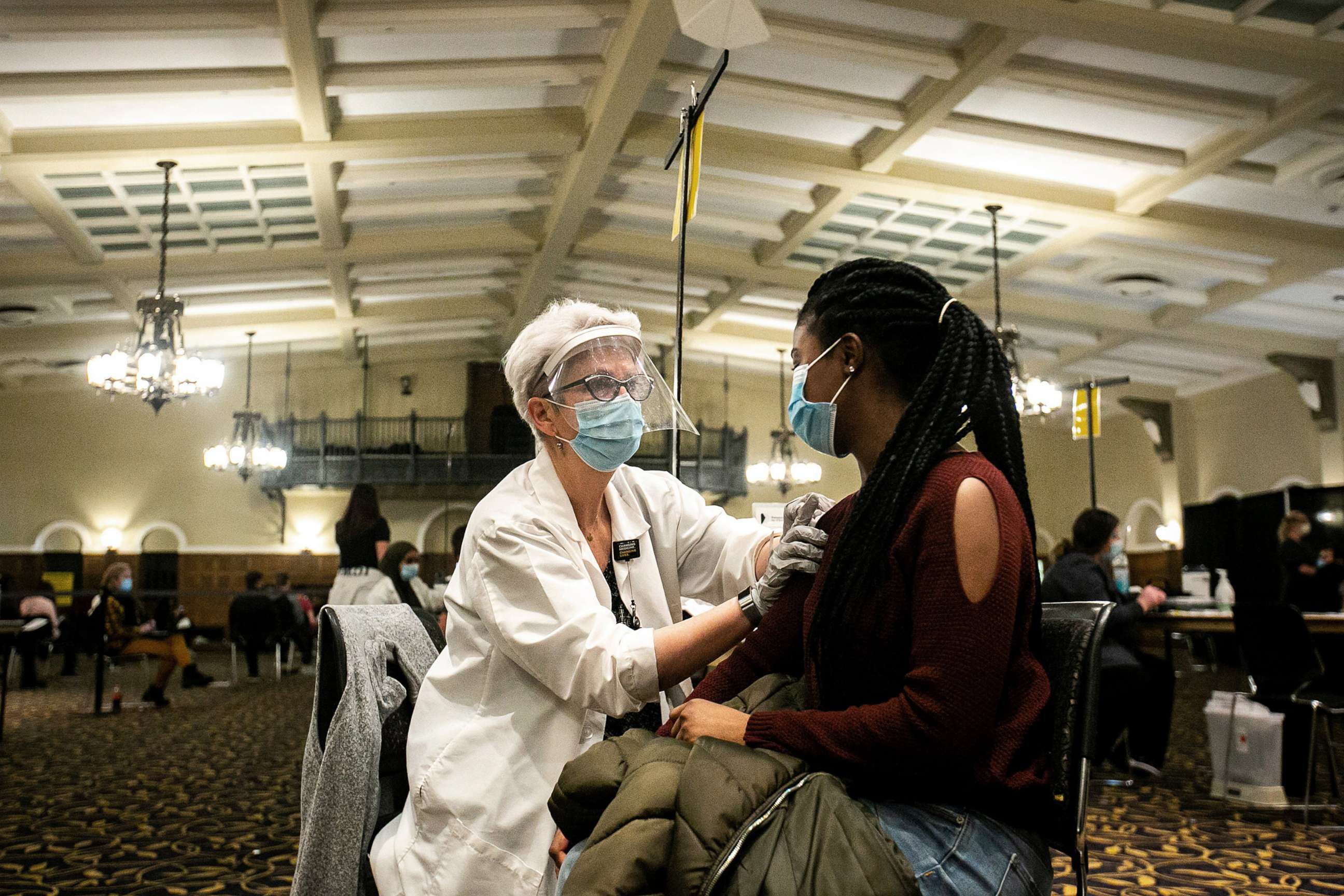 PHOTO: University of Iowa graduate student Precious Cummings, right, receives her first dose of the Pfizer-BioNTech COVID-19 vaccine from volunteer Paula Forest during a vaccination clinic, April 21, 2021, at the Iowa Memorial Union in Iowa City, Iowa.