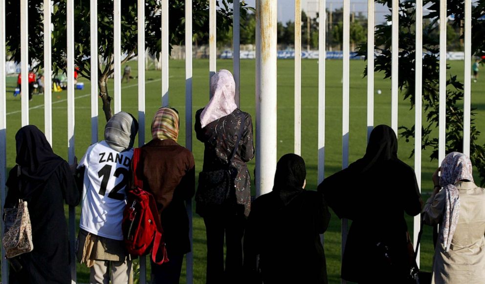 PHOTO: FILE - Iranian women watch a training session of Iran's national football team from behind a fence as females were not allowed to enter the stadium at Tehran's Azadi (Freedom) sport complex, 22 May 2006.