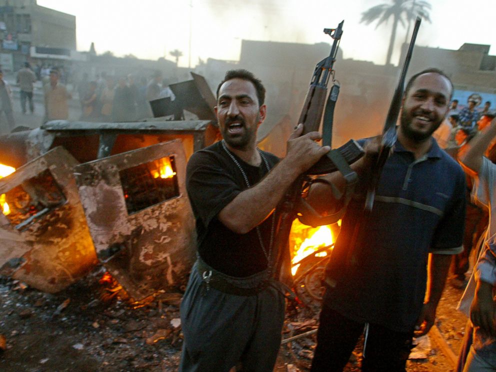 PHOTO: Armed Iraqi Muslim Shiites, member of Shiite radical leader Moqtada al-Sadr Army of Mehdi militia jubilate near a burning US Army Humvee during clashes in Baghdads al-Sadr City district, April 4, 2004.