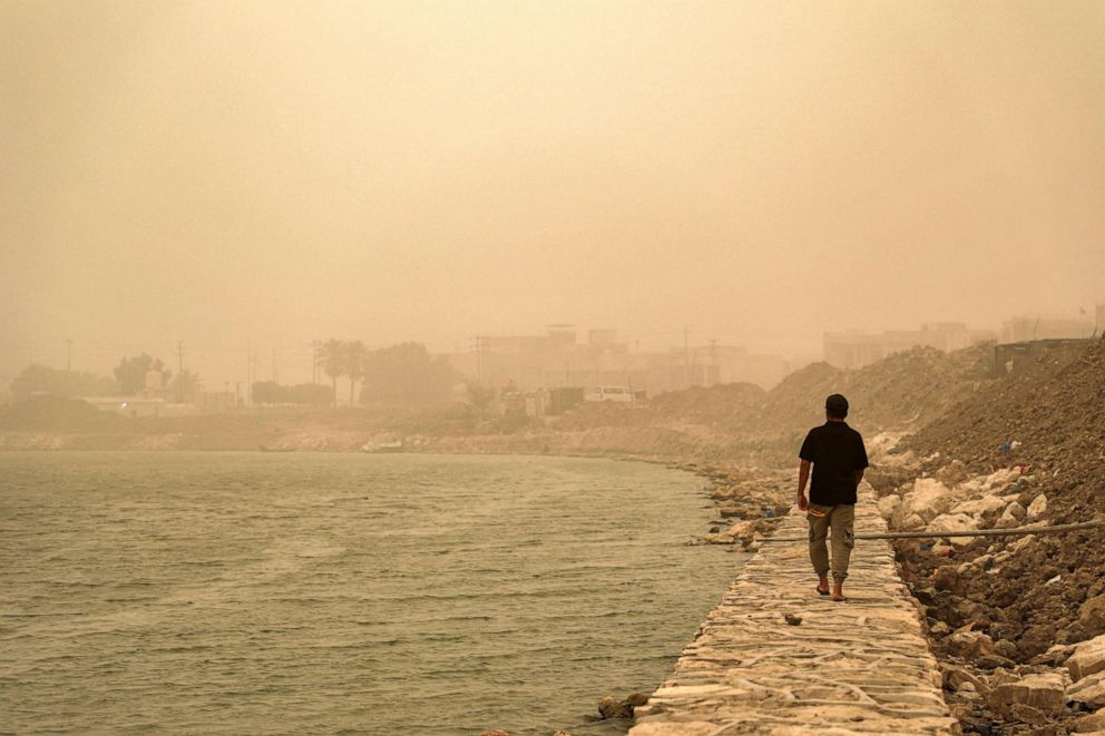 PHOTO: A man walks along a bank of the Euphrates river amidst a heavy dust storm in Nasiriyah, Iraq, August 10, 2022.