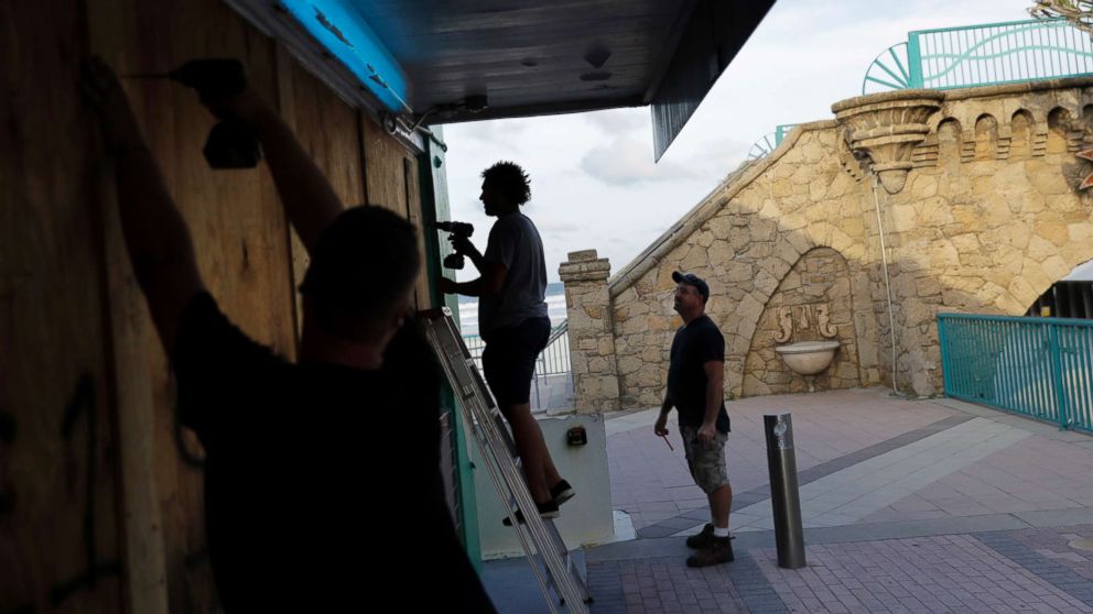 Ryan Otway, from right, Matthew Thames, and Spencer Taylor board up a pizza restaurant on the boardwalk ahead of Hurricane Irma in Daytona Beach, Fla., Sept. 7, 2017. South Florida officials are expanding evacuation orders as Hurricane Irma approaches, telling more than a half-million people to seek safety inland.