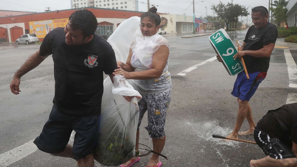 People clear debris out of a drainage ditch in an attempt to keep the area from flooding as Hurricane Irma passes through on Sept. 10, 2017 in Miami.