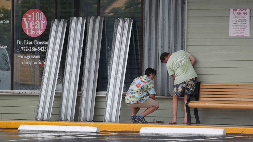 PHOTO: Donald Bowen, left, and Doug Smith put shutters over the windows of their business as Tropical Storm Isaias approaches on Aug. 1, 2020 in Stuart, Fla.