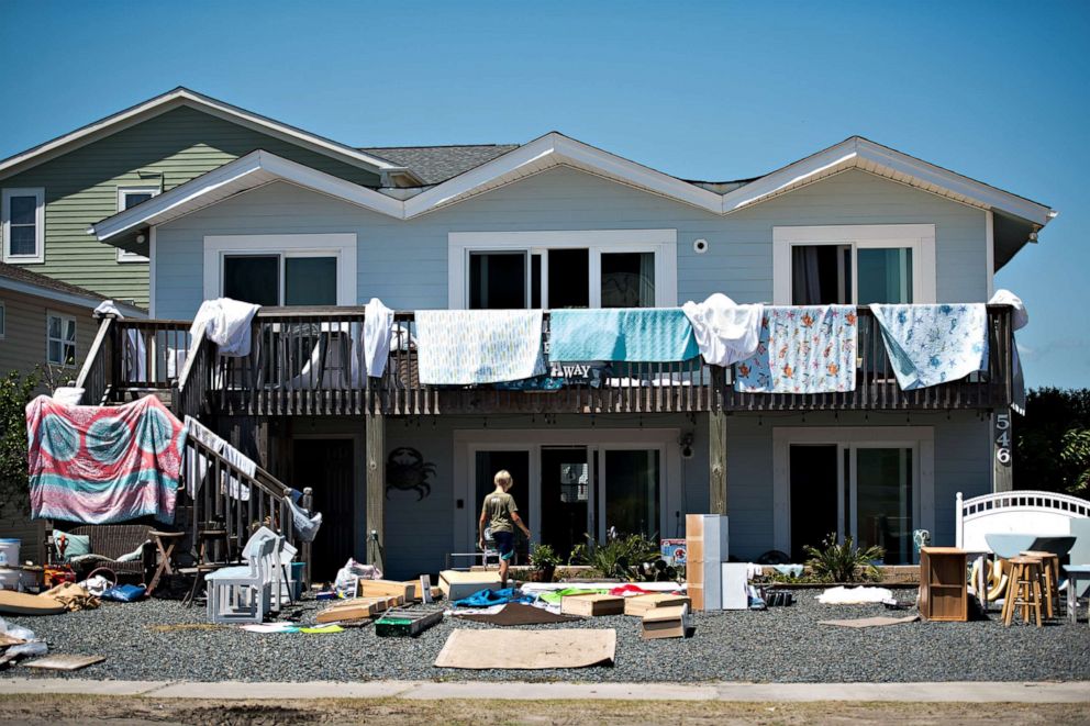 PHOTO: A boy walks in front of a home with items laid out to dry following the previous nights storm surge from Hurricane Isaias on Aug. 4, 2020, in Holden Beach, N.C.
