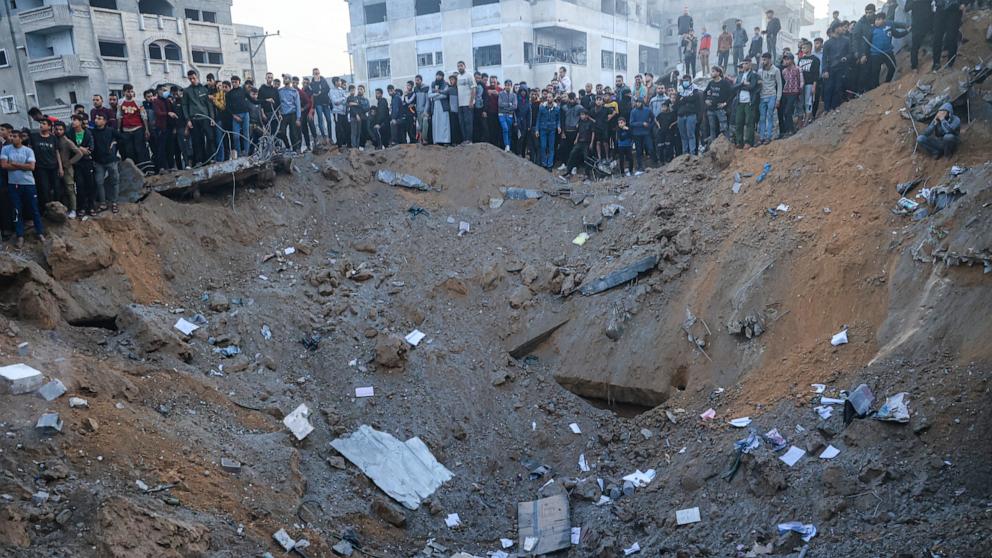 PHOTO: Palestinians stand on the edge of a crater after an Israeli strike in Rafah in the southern Gaza Strip on Dec. 3, 2023, amid continuing battles between Israel and the militant group Hamas. 