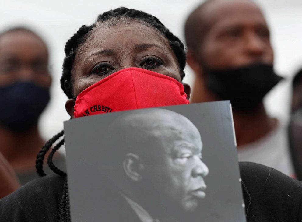 PHOTO: Patrice Houston holds a picture of the late Rep. John Lewis while standing outside the Ebenezer Baptist Church before his funeral service, July 30, 2020, in Atlanta.