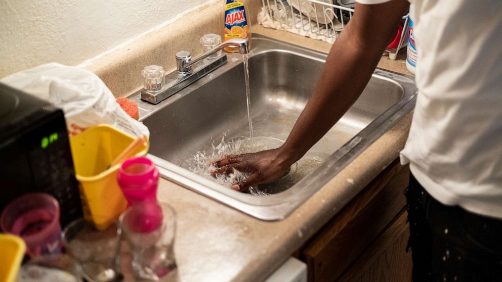 PHOTO: Terrence Carter mixes bleach and soap into the water before washing dishes in response to the water crisis, Sept. 1, 2022, in Jackson, Miss.