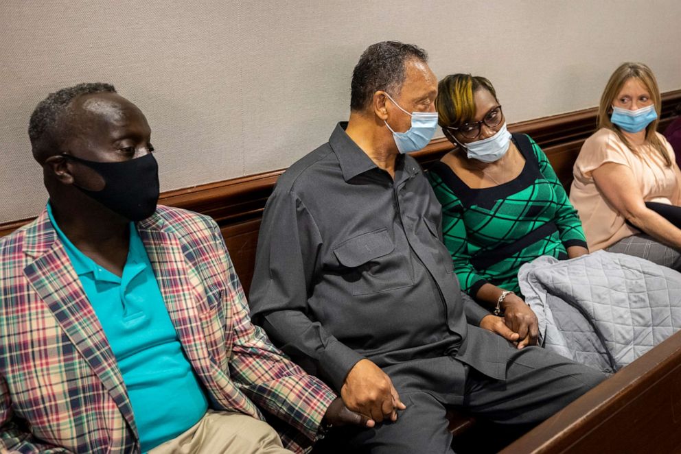 PHOTO: The Rev. Jesse Jackson, center, holds hands with Marcus Arbery, center, father of Ahmaud Arbery, left, Ahmaud Arbery's mother, Wanda Cooper-Jones, right,  in the Glynn County Courthouse, Nov. 15, 2021, in Brunswick, Ga.