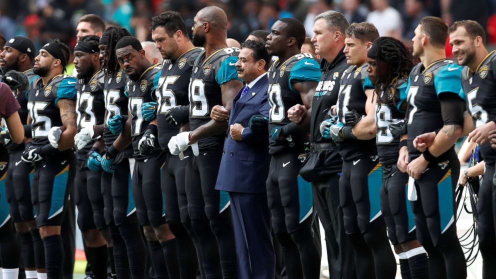 PHOTO: Jacksonville Jaguars owner Shahid Khan links arms with players during the playing of the U.S. national anthem before an NFL football game against the Baltimore Ravens at Wembley Stadium in London, Sept. 24, 2017. 