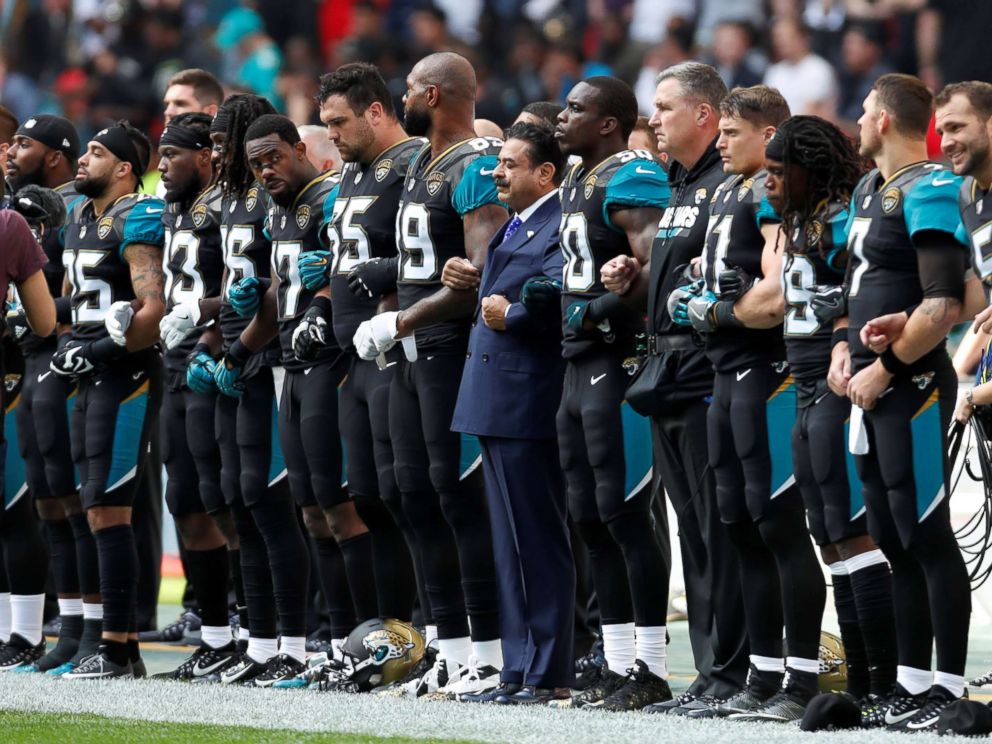 PHOTO: Jacksonville Jaguars owner Shahid Khan links arms with players during the playing of the U.S. national anthem before an NFL football game against the Baltimore Ravens at Wembley Stadium in London, Sept. 24, 2017. 