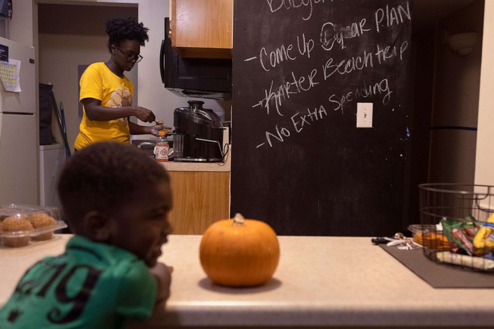 PHOTO: Jane Johnson prepares dinner for her son Karter at their apartment, Oct. 27, 2021 in Birmingham, Ala. A written note on Johnson's wall reminds her not to spend money.
