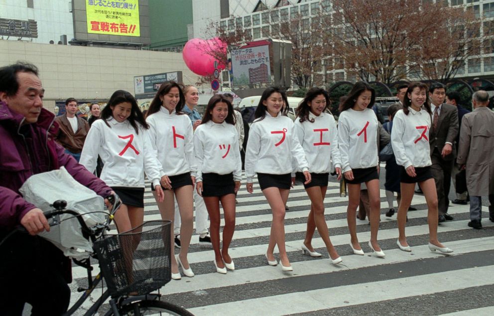 PHOTO: With a heart-shaped red baloon marking the World AIDS Day floating over a square, seven women in mini-skirts and white sweat shirts with red Japanese letters reading "Stop AIDS" march through Tokyo streets Friday, Dec. 1, 1995.