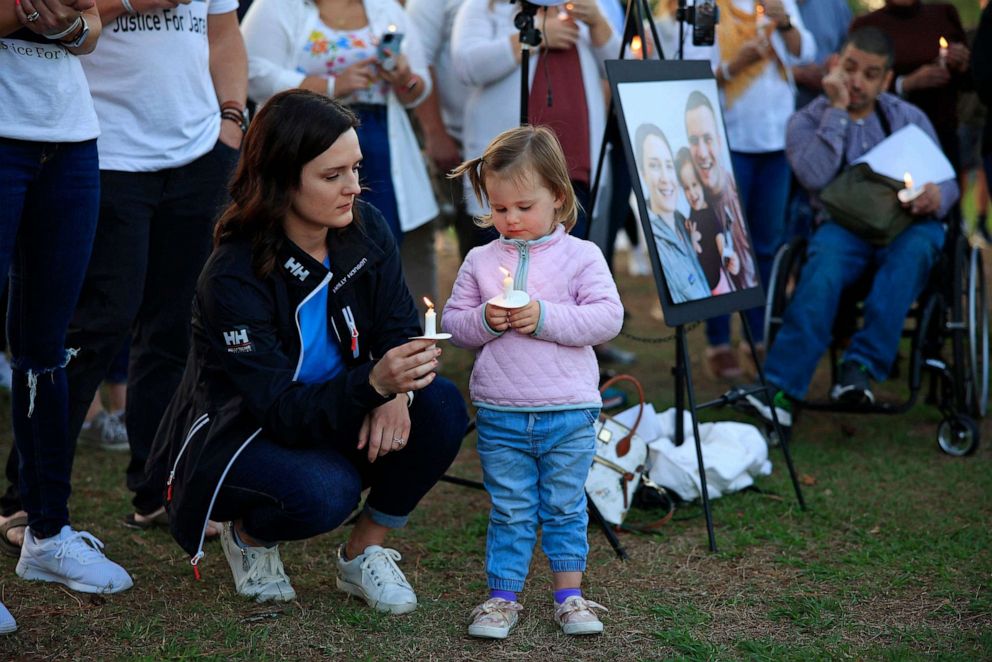 PHOTO: In this April 19, 2022 file photo, Kirsten Bridegan and her 2-year-old daughter Bexley Bridegan look into their candle flames during a vigil at South Beach Park and Sunshine Playground in Jacksonville Beach.