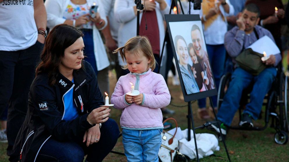 PHOTO: Kirsten Bridegan and her daughter Bexley Bridegan, look at the flames on their candles during a vigil for Jared Bridegan, April 19, 2022, at South Beach Park and Sunshine Playground in Jacksonville Beach, Fla.
