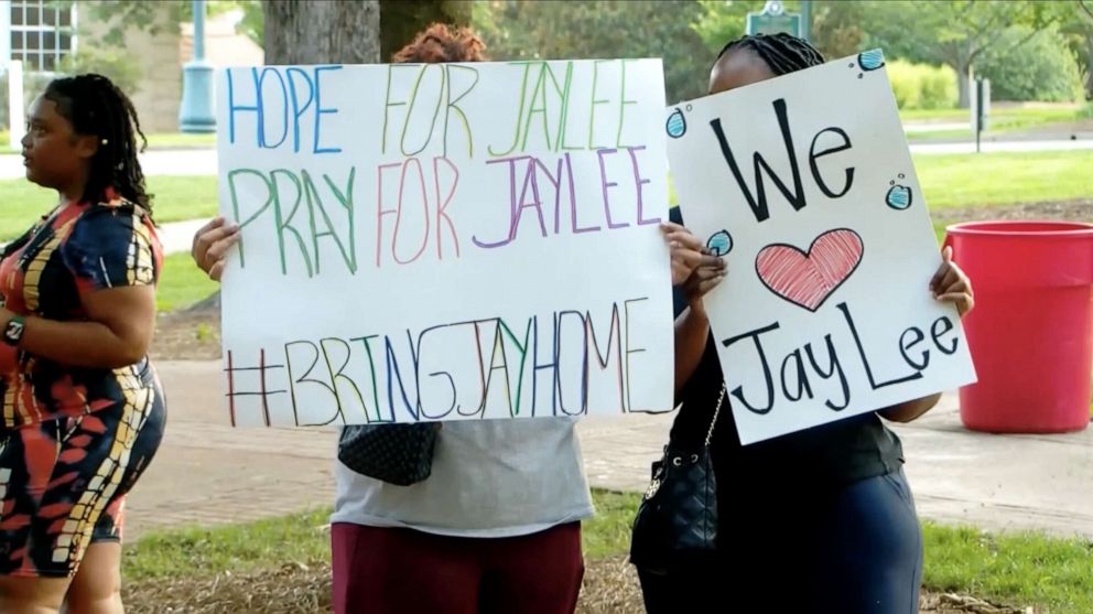 PHOTO: Two attendees are shown holding posters in support of Lee's safe return home.