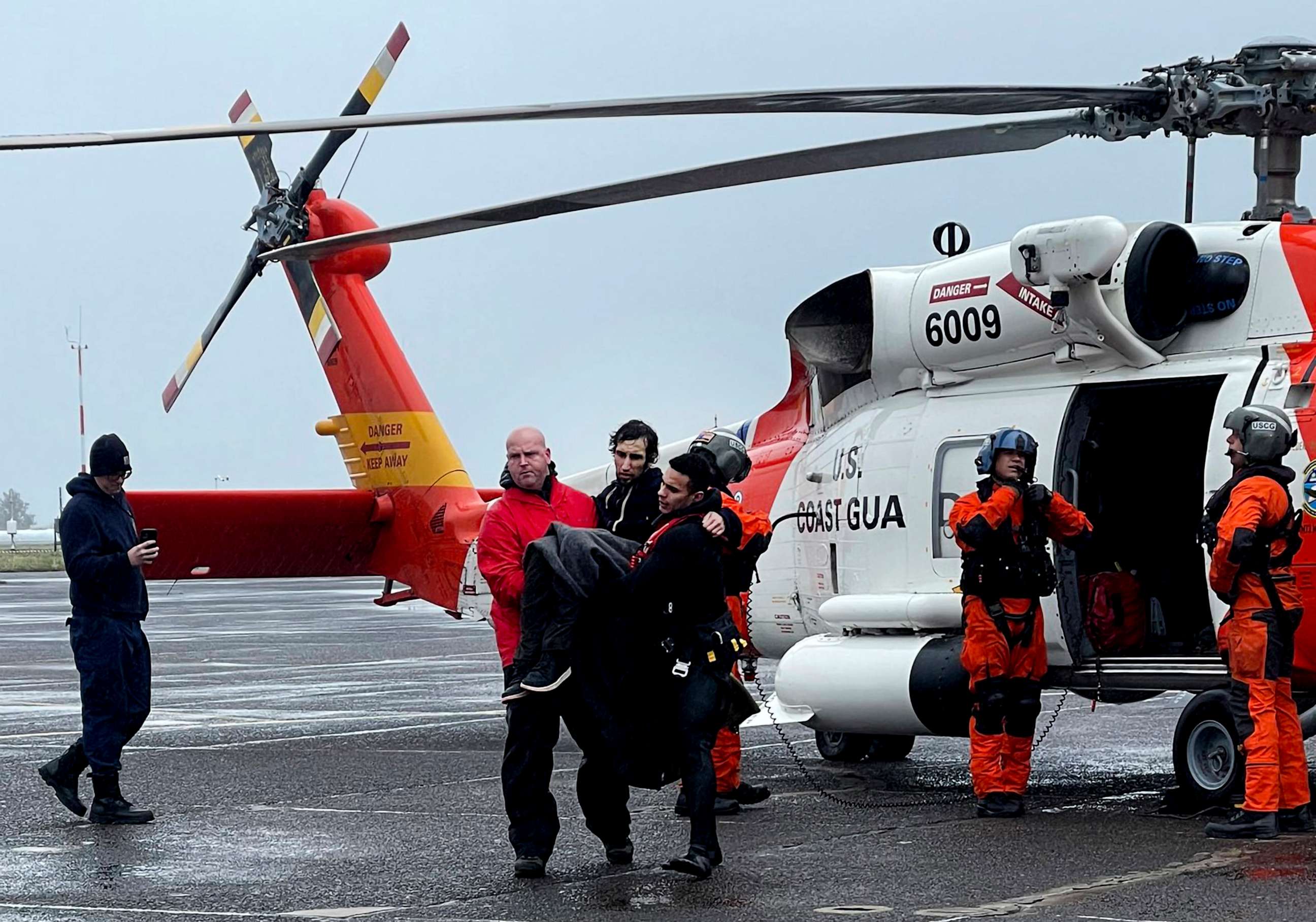 PHOTO: In this photo provided by the U.S Coast Guard Pacific Northwest, Coast Guard personnel help carry a swimmer from a rescue helicopter after he was rescued from the mouth of the Columbia River on Feb. 3, 2023, at Coast Guard Base Astoria, Oregon.