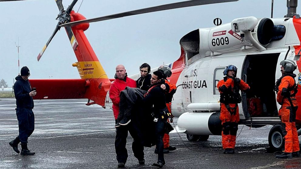 PHOTO: In this photo provided by the U.S Coast Guard Pacific Northwest, Coast Guard personnel help carry a swimmer from a rescue helicopter after he was rescued from the mouth of the Columbia River on Feb. 3, 2023, at Coast Guard Base Astoria, Oregon.