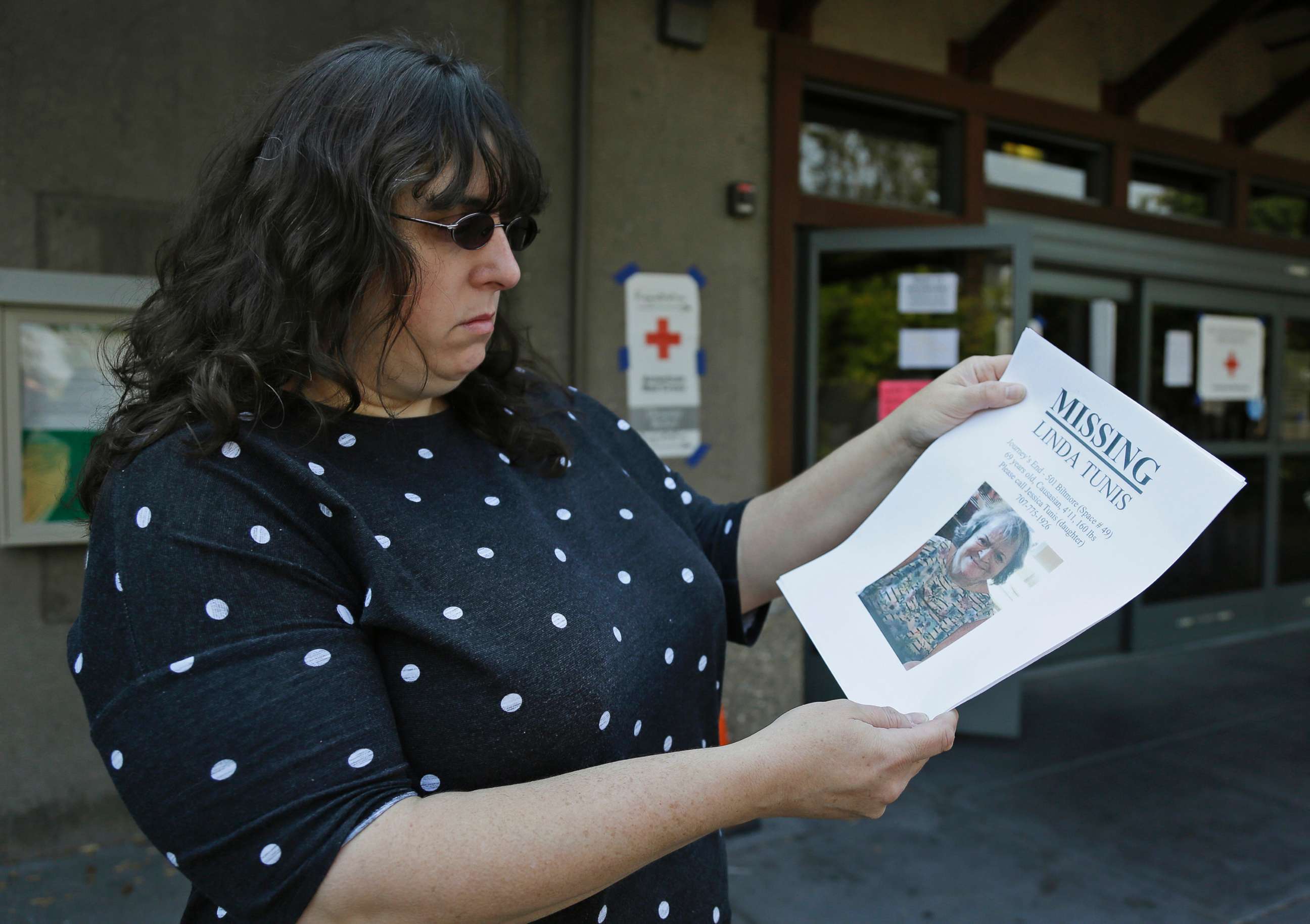 PHOTO: Jessica Tunis stands outside a Red Cross evacuation center and holds a flyer about her missing mother, Oct. 11, 2017, in Santa Rosa, Calif.