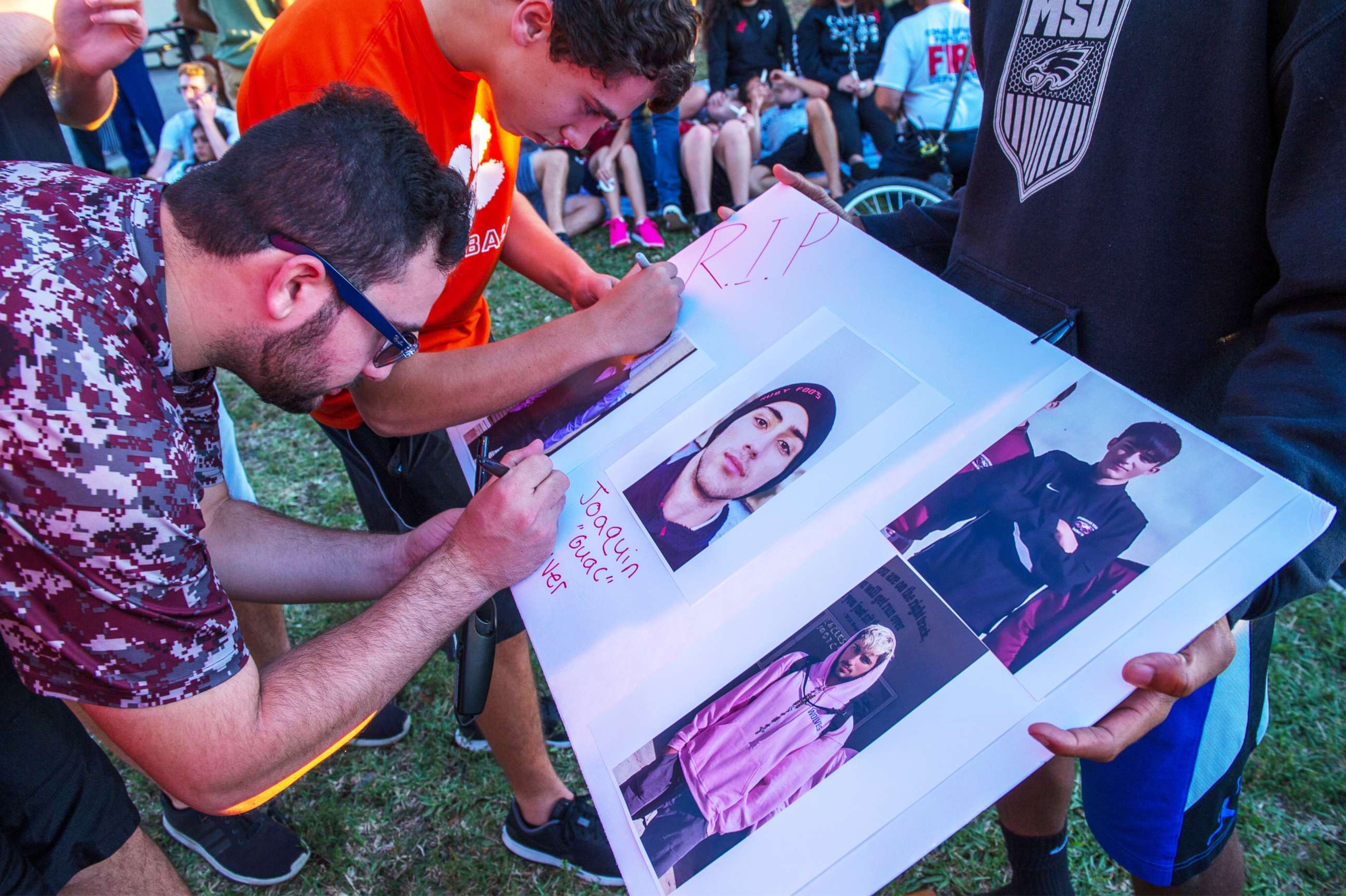 PHOTO: Students sign a poster with photos of Joaquin Oliver, one of the victims of a school shooting, during a candlelight vigil at the Amphitheater at Pine Trails Park, Parkland, Fla., Feb. 15, 2018.