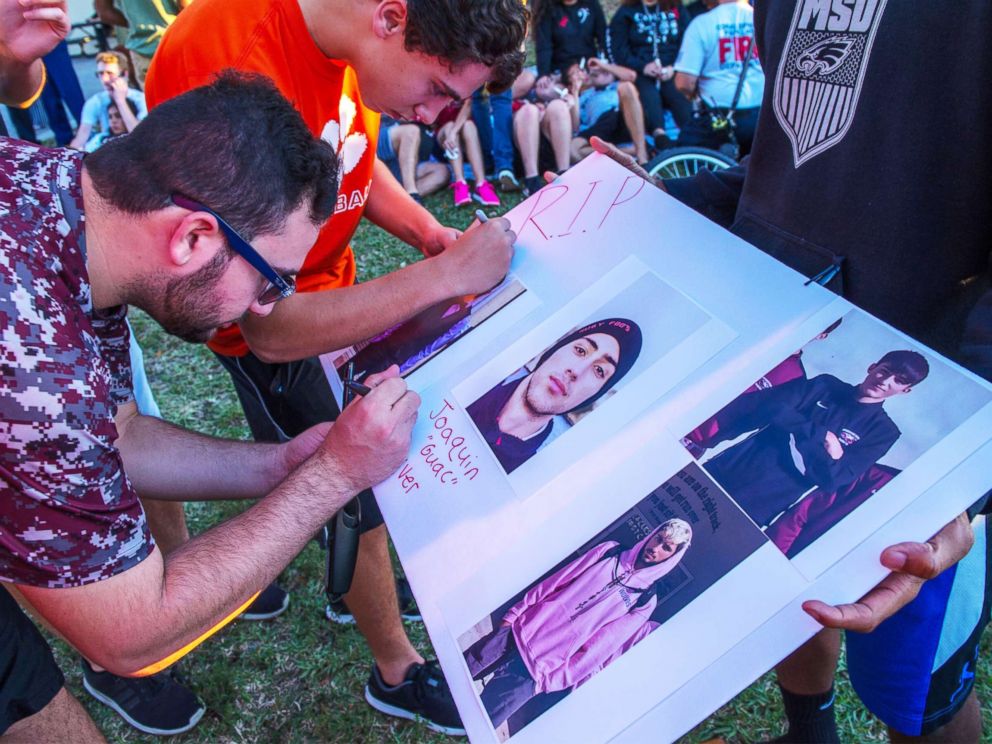 PHOTO: Students sign a poster with photos of Joaquin Oliver, one of the victims of a school shooting, during a candlelight vigil at the Amphitheater at Pine Trails Park, Parkland, Fla., Feb. 15, 2018.