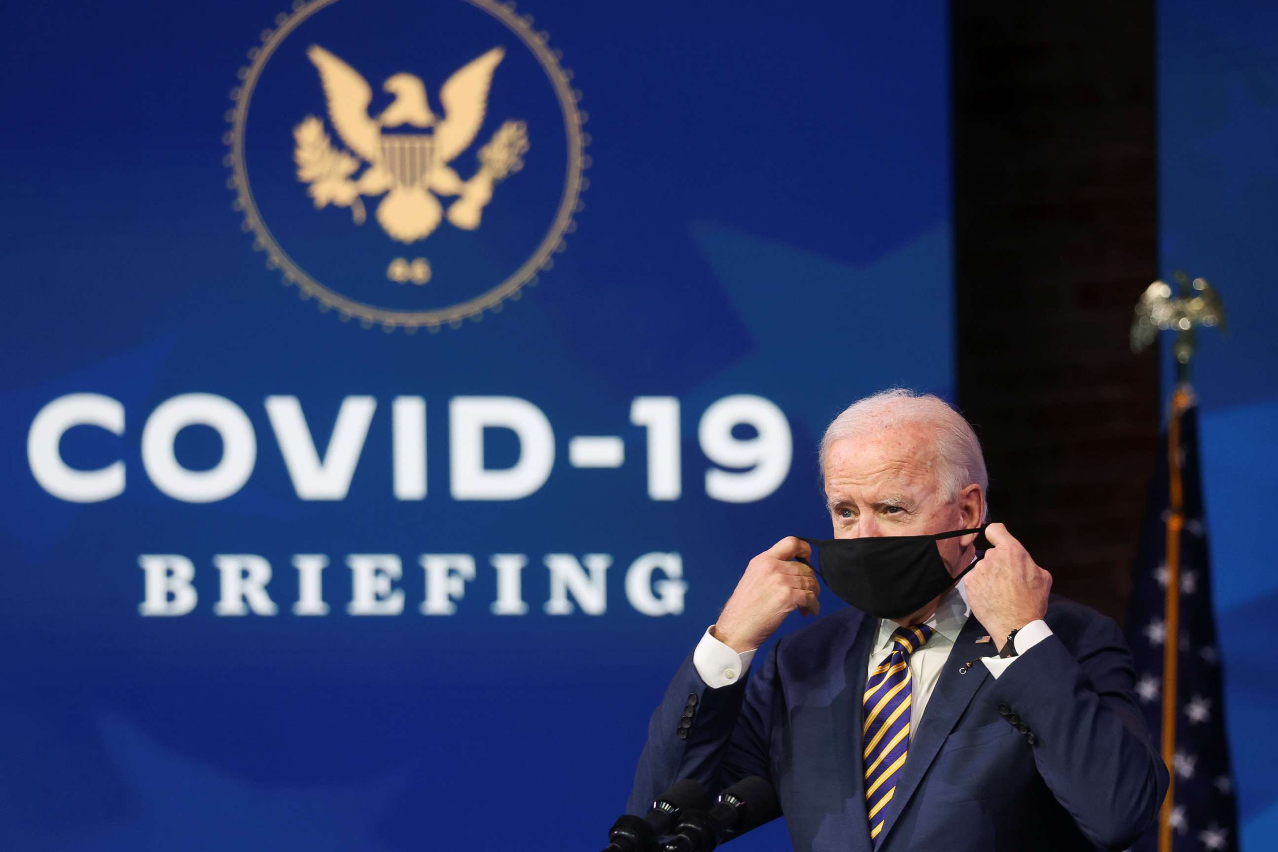 PHOTO: President-elect Joe Biden takes off his face mask to deliver remarks on the country's response to the coronavirus disease outbreak, at his transition headquarters in Wilmington, Del., Dec. 29, 2020.