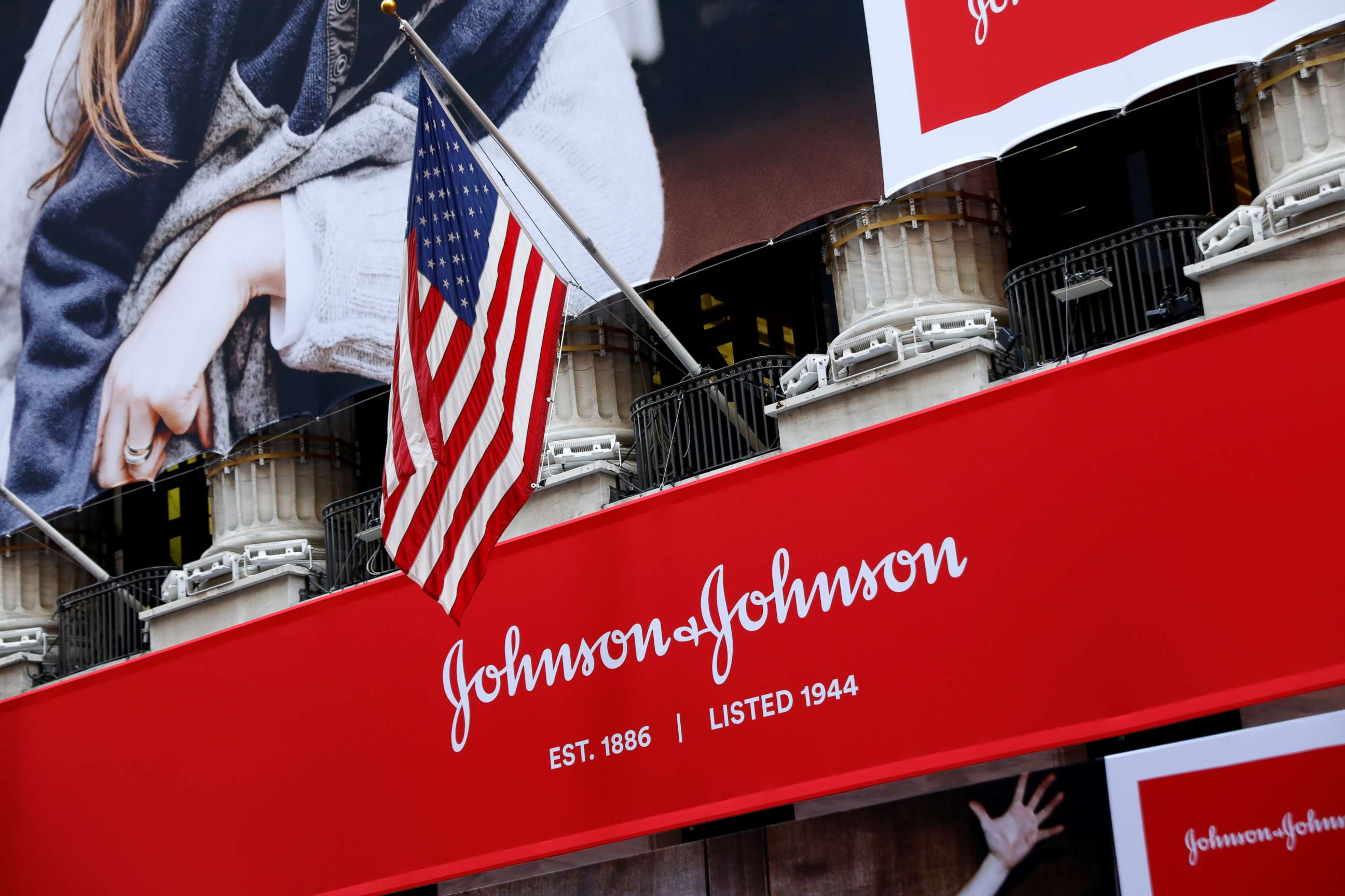 PHOTO: The U.S. flag is seen over the company logo for Johnson & Johnson to celebrate the 75th anniversary of the company's listing at the New York Stock Exchange (NYSE).