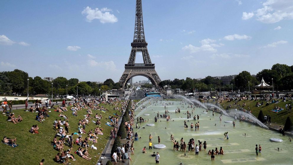 PHOTO: In this file photo taken on July 25, 2019, people cool off and sunbathe by the Trocadero Fountains next to the Eiffel Tower in Paris, as a new heatwave hits the French capital.