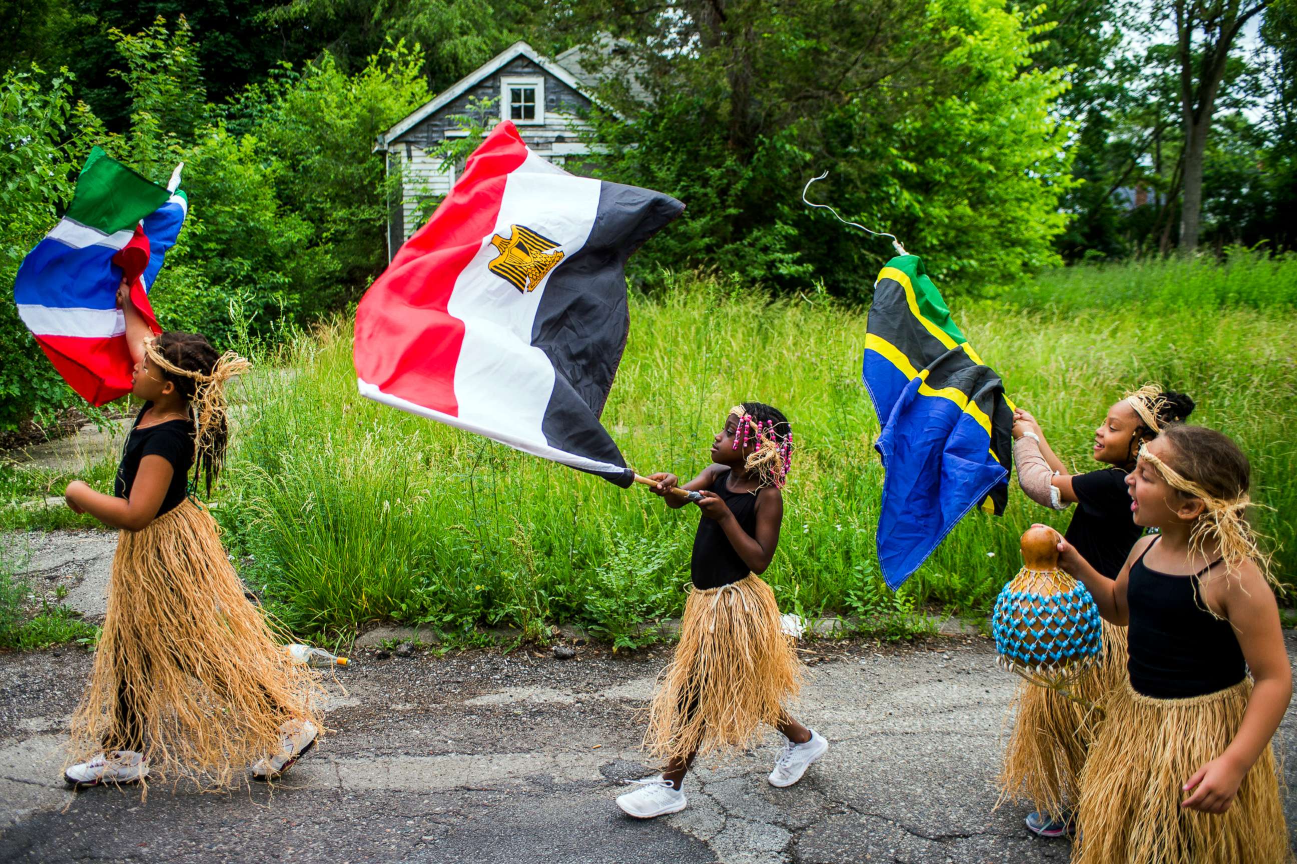 PHOTO: In this June 19, 2018, file photo, girls wave flags as they march along Pasadena Avenue in a parade from Max Brandon Park to University Park, celebrating Juneteenth in Flint, Mich.