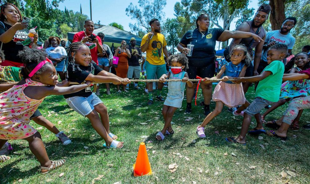 PHOTO: Children compete in a tug-a-war as they are cheered on by parents and others during the Juneteenth Celebration hosted by The B.L.A.C.K. Collective and IOTA PHI THETA at Fairmount Park in Riverside, Calif., June 19, 2021.