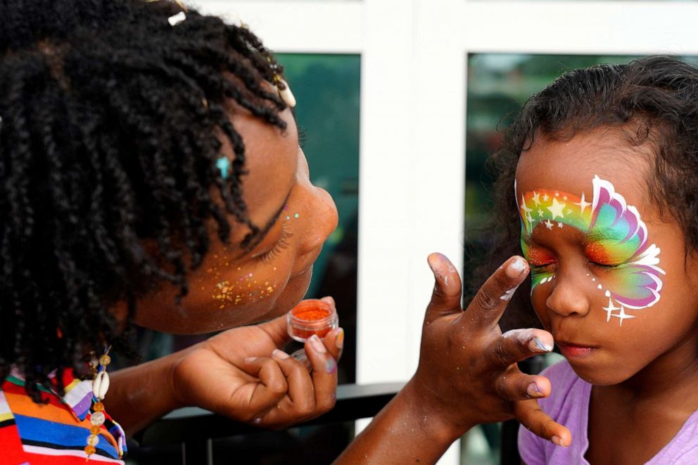 PHOTO: Artist Isha Joseph paints the face of four year old Layla Zephyrin at her booth during the Juneteenth Jam at the Northstar Academies on June 19, 2021, in St. Petersburg, Fla.
