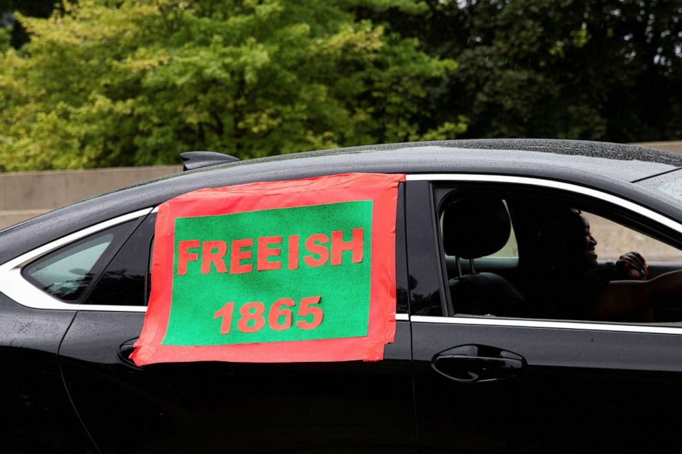 PHOTO: A person drives in the parade with a sign on their car reading "Freeish 1865" as people celebrate Juneteenth in Flint, Mich., June 19, 2021.