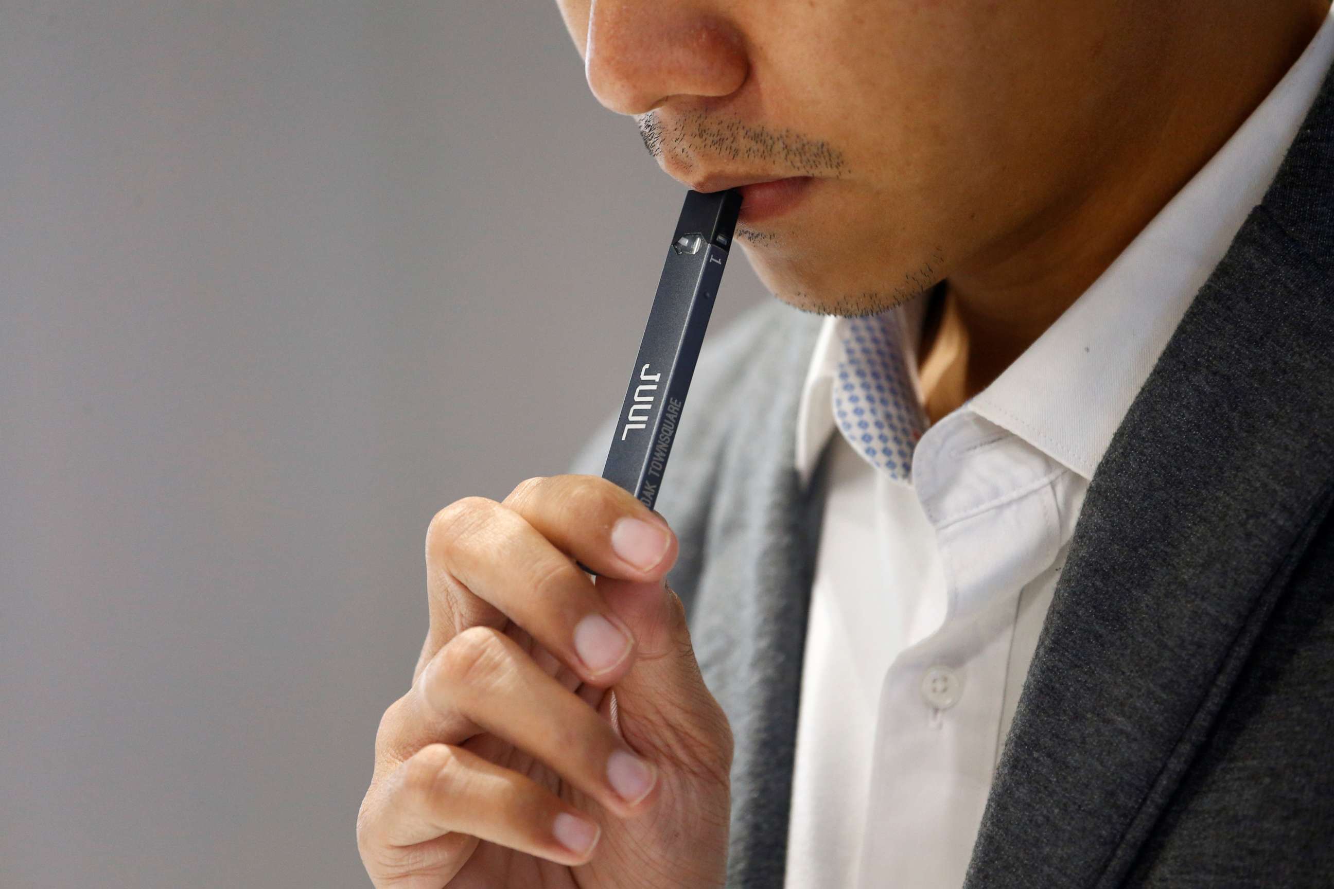 PHOTO: A shopkeeper demonstrates smoking a Juul vaping pen to customers at a Juul shop in Jakarta, Indonesia, Dec. 30, 2019.