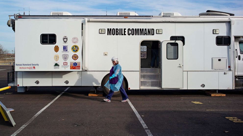 PHOTO: A nurse with the Riley County Health Department walks past the COVID-19 vaccine mobile command center in the parking lot of Bill Snyder Family Stadium at Kansas State University in Manhattan, Kansas, Dec. 22, 2010.