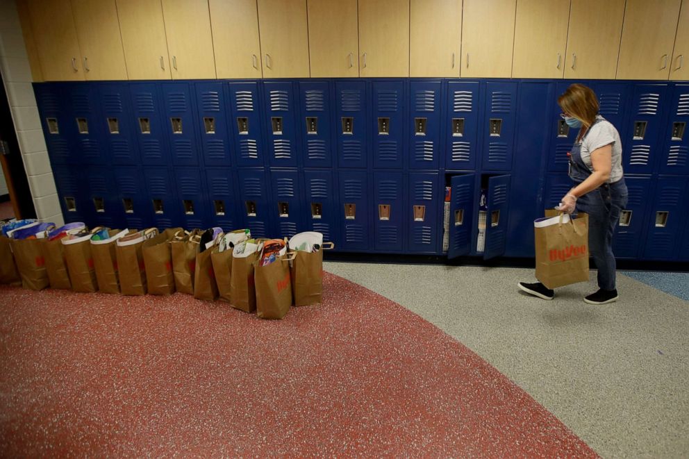 PHOTO: LuAnn Duval places bags of her student's belongings outside her second grade classroom at Walnut Grove Elementary school, May 12, 2020, in Olathe, Kan. 