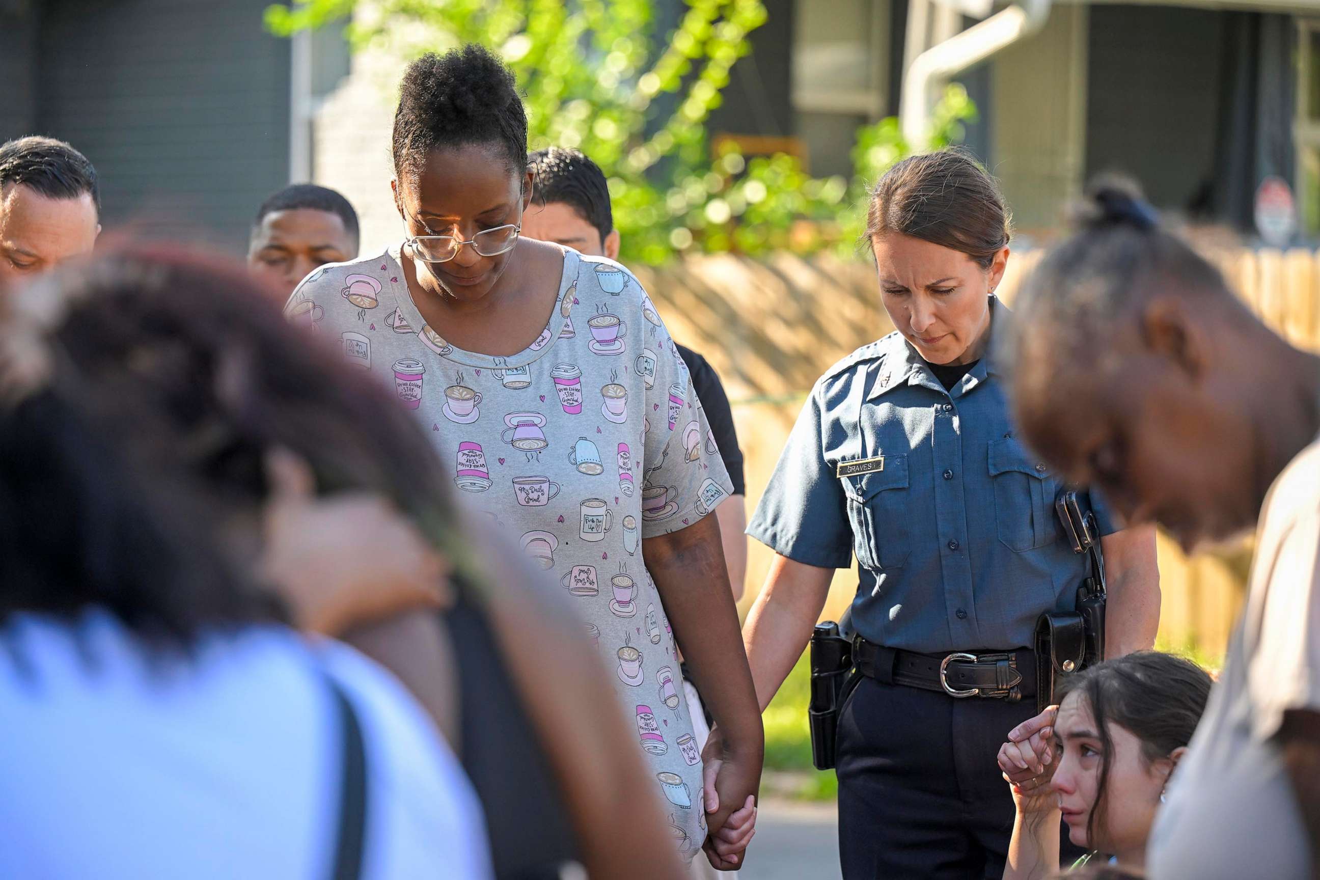 PHOTO: Kansas City Police Chief Stacey Graves held hands with Cherron Barney, left, and another woman as people gathered in the street to pray following a shooting , June 25, 2023, in Kansas City.