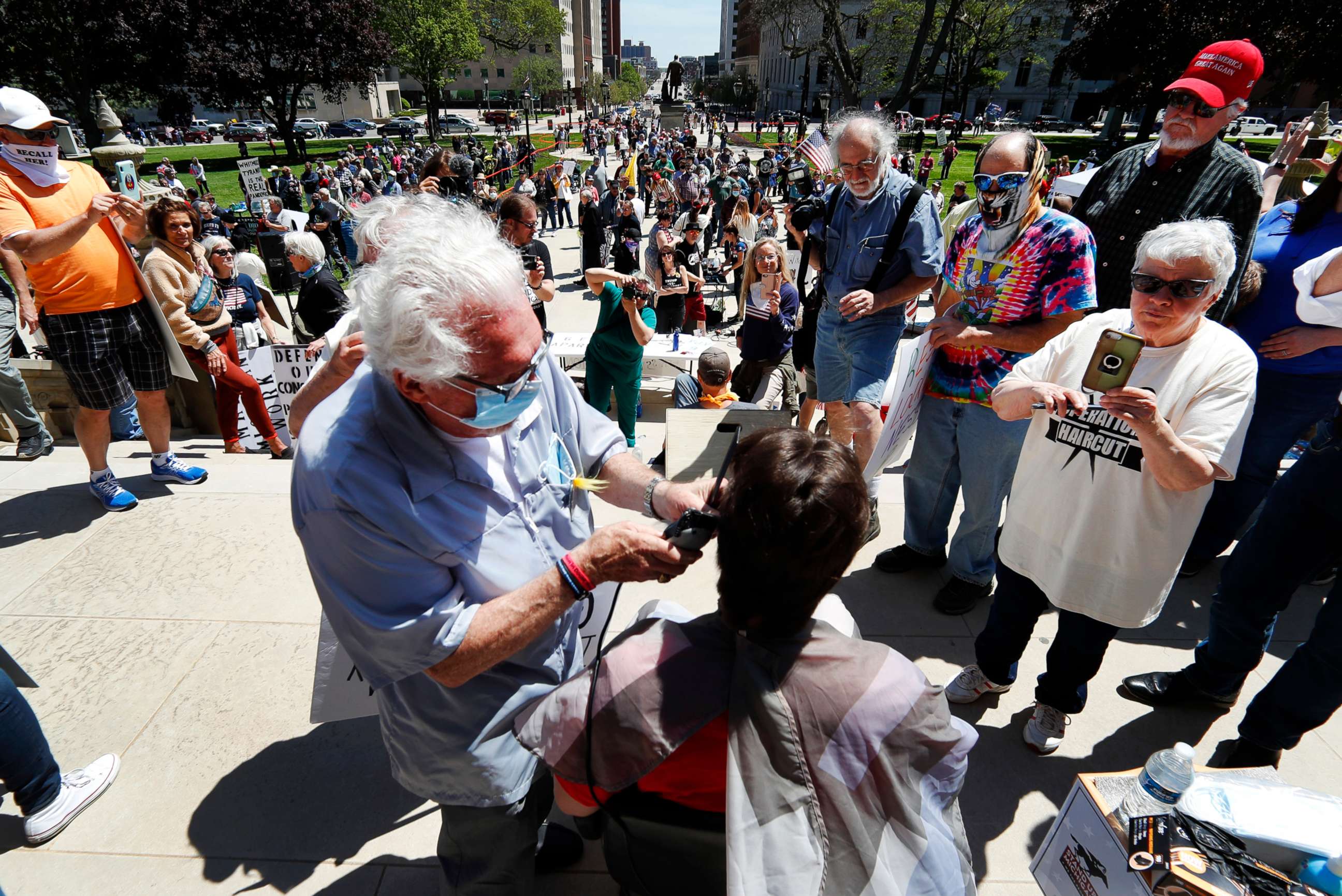 PHOTO: Barber Karl Manke, of Owosso, gives a free haircut on the steps of the State Capitol during a rally in Lansing, Mich., May 20, 2020.