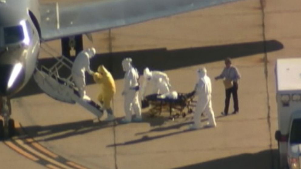 PHOTO: A man without a hazmat suit assists in the transportation of Ebola patient Amber Vinson from an ambulance to a plane at the Dallas airport on Oct 15, 2014.