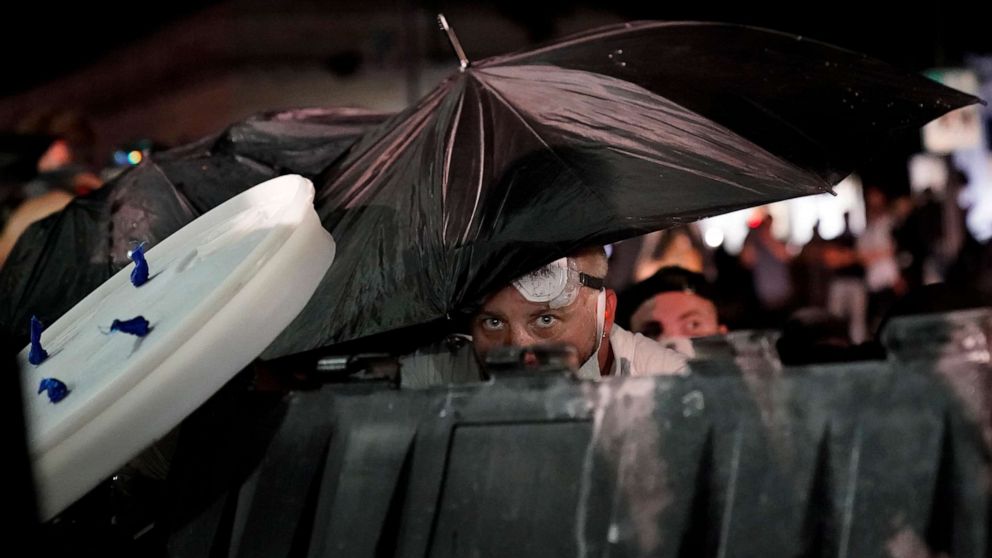 PHOTO: A protester takes cover during clashes outside the Kenosha County Courthouse late Tuesday, Aug. 25, 2020, in Kenosha, Wis.