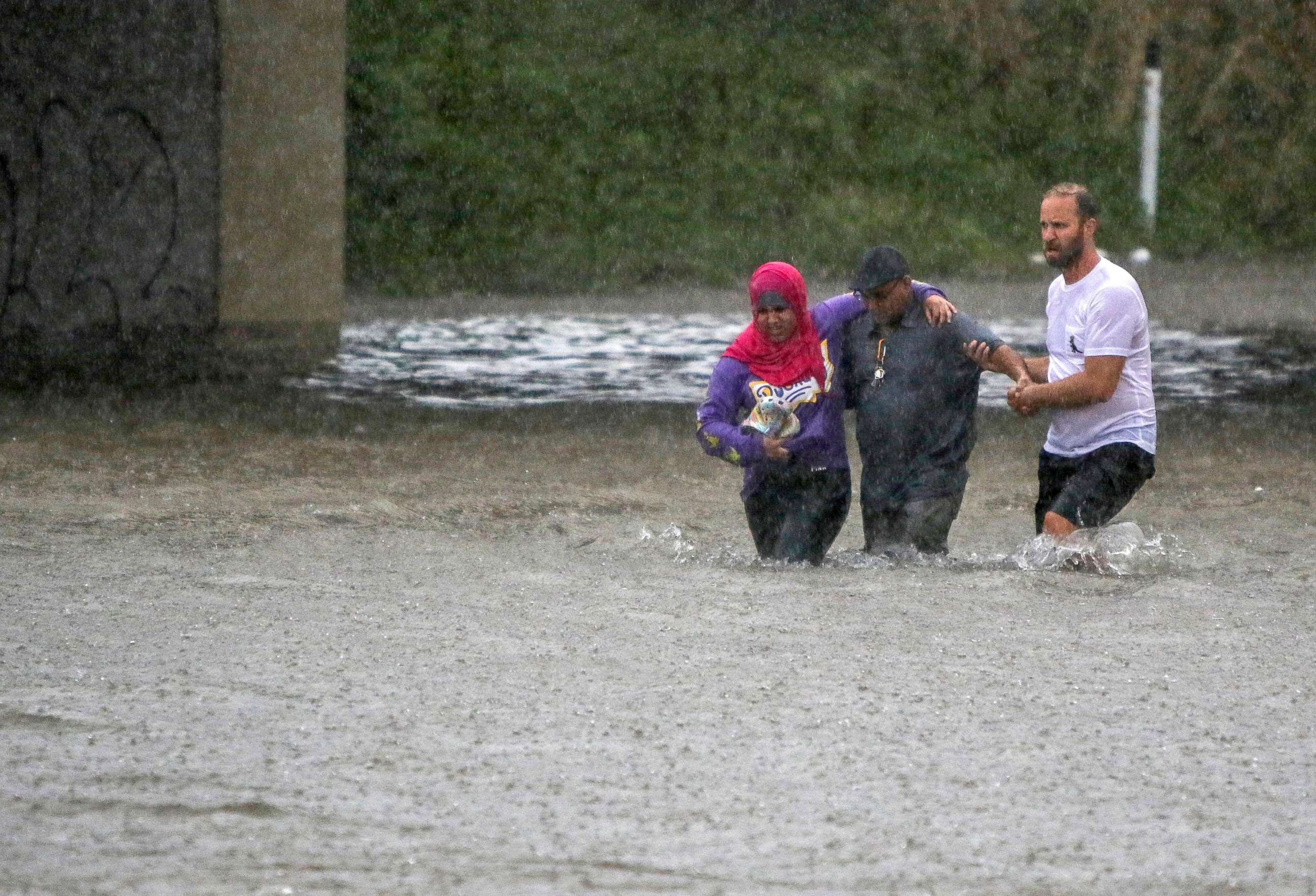PHOTO: A man helps two people walk through flood water after their car got stuck in St. Louis, Mo., July 28, 2022.