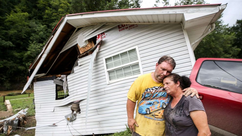 PHOTO: Reggie Ritchie comforts wife, Della, as they pause while clearing out their home destroyed by the flooding from Troublesome Creek behind them in Fisty, Kentucky, on July 29, 2022.