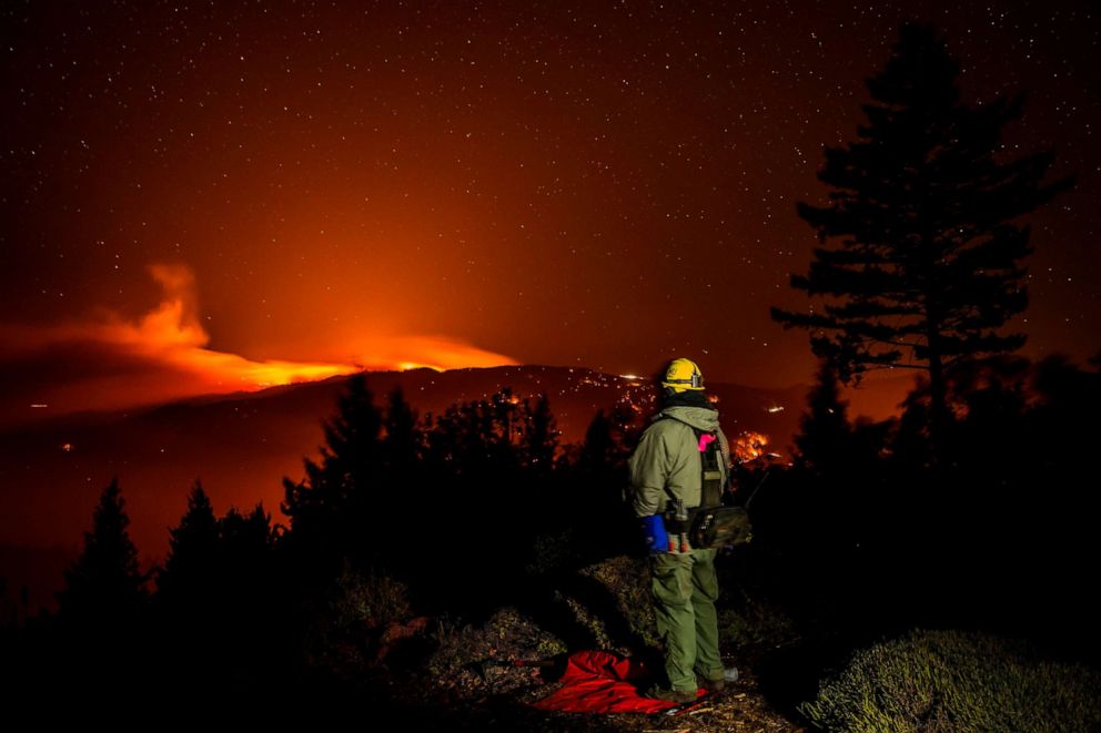 PHOTO: A man watches the Kincade fire burn on a ridge between Lake and Sonoma Counties, as he stands watch at a home above Knights Valley, east of Healdsburg, Calif., Oct. 29, 2019.