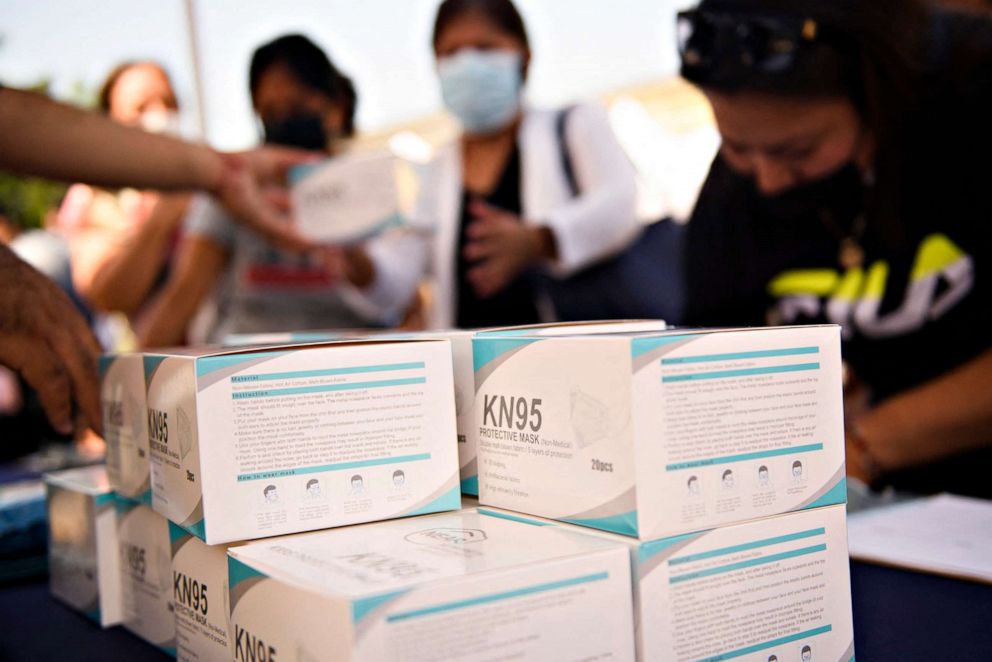 Families receive boxes of KN95 face masks during a back to school event offering school supplies, COVID-19 vaccinations, face masks, and other resources for children and their families at the Weingart East Los Angeles YMCA in Los Angeles on Aug. 7, 2021. 